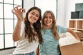 Young beautiful couple smiling happy holding cardboard box and key of new home Royalty Free Stock Photo
