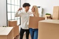 Young beautiful couple smiling happy holding cardboard box and key of new home Royalty Free Stock Photo