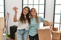 Young beautiful couple smiling happy holding cardboard box and key of new home Royalty Free Stock Photo