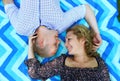 Young beautiful couple smiling and lying on the blanket on the grass in the park. Royalty Free Stock Photo