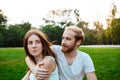 Young beautiful couple smiling, sitting on grass in park. Outdoor background. Royalty Free Stock Photo