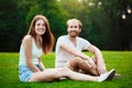 Young beautiful couple smiling, sitting on grass in park. Outdoor background. Royalty Free Stock Photo