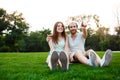 Young beautiful couple smiling, sitting on grass in park. Outdoor background. Royalty Free Stock Photo