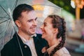 Young beautiful couple spending time together on date in amusement park at night. Rainy weather, autumn. Lovers standing Royalty Free Stock Photo