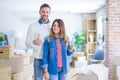 Young beautiful couple standing at new home around cardboard boxes doing happy thumbs up gesture with hand Royalty Free Stock Photo