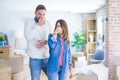 Young beautiful couple standing at new home around cardboard boxes smelling something stinky and disgusting, intolerable smell, Royalty Free Stock Photo