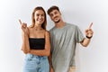 Young beautiful couple standing together over isolated background with a big smile on face, pointing with hand finger to the side Royalty Free Stock Photo