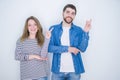 Young beautiful couple standing together over white isolated background with a big smile on face, pointing with hand and finger to Royalty Free Stock Photo