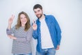 Young beautiful couple standing together over white isolated background smiling with happy face winking at the camera doing Royalty Free Stock Photo