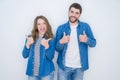 Young beautiful couple standing together over white isolated background success sign doing positive gesture with hand, thumbs up Royalty Free Stock Photo