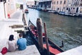Young beautiful couple taking rest in the city of Venice waiting the gondolier for a journey in gondola - Italy