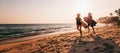 Young beautiful couple walking along the sandy beach near the ocean at sunset with surfboards, outdoor activities and sports Royalty Free Stock Photo