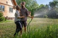 Young beautiful couple watering the plants in a country house, summer, work in the garden, love and summer concept