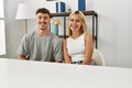 Young beautiful couple wearing casual clothes sitting on the table at home looking positive and happy standing and smiling with a Royalty Free Stock Photo