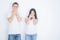 Young beautiful couple wearing casual t-shirt standing over isolated white background shocked covering mouth with hands for Royalty Free Stock Photo