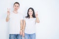 Young beautiful couple wearing casual t-shirt standing over isolated white background smiling with happy face winking at the Royalty Free Stock Photo