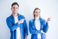 Young beautiful couple wearing denim shirt standing over isolated white background with a big smile on face, pointing with hand Royalty Free Stock Photo