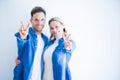 Young beautiful couple wearing denim shirt standing over isolated white background smiling with happy face winking at the camera Royalty Free Stock Photo