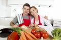 Young beautiful couple working at home kitchen preparing vegetable salad together smiling happy Royalty Free Stock Photo