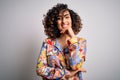 Young beautiful curly arab woman wearing floral colorful shirt standing over white background looking confident at the camera with Royalty Free Stock Photo