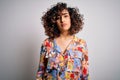 Young beautiful curly arab woman wearing floral colorful shirt standing over white background Relaxed with serious expression on Royalty Free Stock Photo