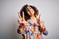 Young beautiful curly arab woman wearing floral colorful shirt standing over white background smiling looking to the camera Royalty Free Stock Photo