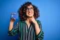 Young beautiful curly arab woman wearing glasses holding credit card money for payment serious face thinking about question, very Royalty Free Stock Photo