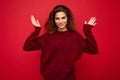 Young beautiful curly brunette woman with sincere emotions poising isolated on background wall with copy space wearing Royalty Free Stock Photo