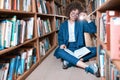 Young beautiful curly girl in glasses and blue suit sitting with books in the library. Royalty Free Stock Photo