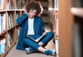 Young beautiful curly girl in glasses and blue suit sitting with books in the library. Royalty Free Stock Photo