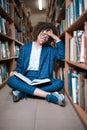 Young beautiful curly girl in glasses and blue suit sitting with books in the library. Royalty Free Stock Photo