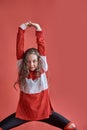 Young beautiful cute girl dancing on red background, modern slim hip-hop style teenage girl jumping Royalty Free Stock Photo
