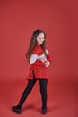 Young beautiful cute girl dancing on red background, modern slim hip-hop style teenage girl jumping