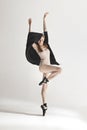 Young beautiful dancer in beige swimsuit dancing on gray background