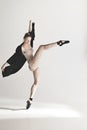 Young beautiful dancer in beige swimsuit dancing on gray background