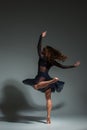 Young beautiful dancer in black dress posing on a dark gray studio background Royalty Free Stock Photo