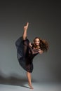 Young beautiful dancer in black dress posing on a dark gray studio background Royalty Free Stock Photo