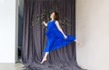Young beautiful dancer in blue dress posing on a dance shool background