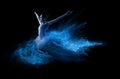Young beautiful dancer jumping into blue powder cloud
