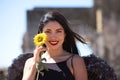 A young, beautiful, dark-haired latin woman with black angel wings in a ruined city clutches a sunflower in her hands. The woman Royalty Free Stock Photo