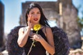 A young, beautiful, dark-haired latin woman with black angel wings in a ruined city clutches a sunflower in her hands. The woman Royalty Free Stock Photo