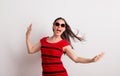 A young beautiful delighted woman with red sunglasses and t-shirt in a studio.