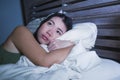 Young beautiful depressed and sad Asian Chinese woman having insomnia lying in bed at night sleepless suffering anxiety stress and Royalty Free Stock Photo