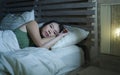 Young beautiful depressed and sad Asian Chinese woman having insomnia lying in bed at night sleepless suffering anxiety stress and Royalty Free Stock Photo