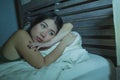 Young beautiful depressed and sad Asian Chinese woman having insomnia lying in bed at night sleepless suffering anxiety stress and Royalty Free Stock Photo