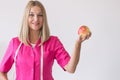 Beautiful dietitian is standing in the office holding an apple