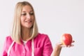 Beautiful dietitian is standing in the office holding an apple