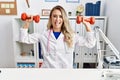 Young beautiful doctor woman holding dumbbells for sport therapy sticking tongue out happy with funny expression Royalty Free Stock Photo