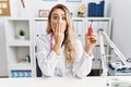 Young beautiful doctor woman holding electronic cigarette at the clinic covering mouth with hand, shocked and afraid for mistake Royalty Free Stock Photo