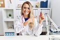 Young beautiful doctor woman holding electronic cigarette at the clinic smiling happy pointing with hand and finger Royalty Free Stock Photo